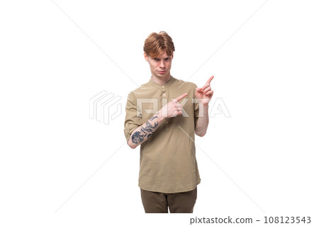 young caucasian man with red hair dressed in a khaki shirt and brown trousers points his hand to the 108123543