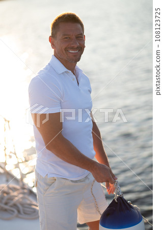 Man in white clothes fixing ropes on a yacht 108123725