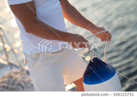 Man in white clothes fixing ropes on a yacht 108123731