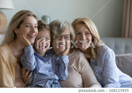 Happy kid, young, mature and elder women relaxing on sofa 108123935