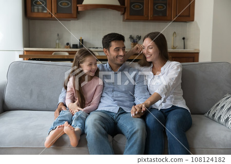 Happy joyful attractive parents and kid girl resting on sofa 108124182