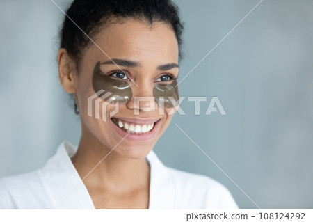 Smiling biracial woman use under eye gel patches Smiling biracial woman use under eye gel patches 108124292