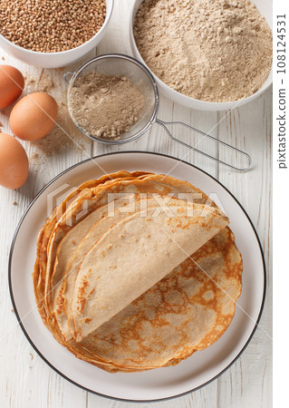 French buckwheat crepes gluten free and with a lovely slightly nutty flavor closeup on the white wooden table. Vertical top view French buckwheat crepes gluten free and with a lovely slightly nutty flavor closeup on the white wooden table. Vertical top view 108124531