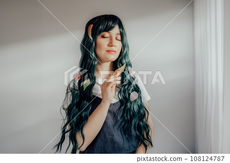 Beautiful tender woman with long dark green hair and multicolored skeleton leaves in ray of sunset light. Attractive fantasy girl, Young elven princess style. A gentle image. Autumn, fall concept. 108124787