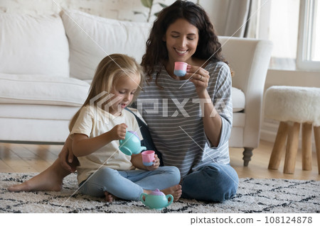 Playful kid and happy mom playing role game on floor Playful kid and happy mom playing role game on floor 108124878