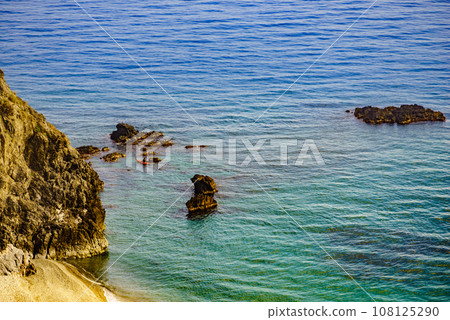 Rocky sea shore with person kayaking Rocky sea shore with person kayaking 108125290