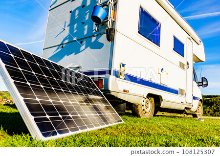 Camper with portable solar panel on coast Camper with portable solar panel on coast 108125307