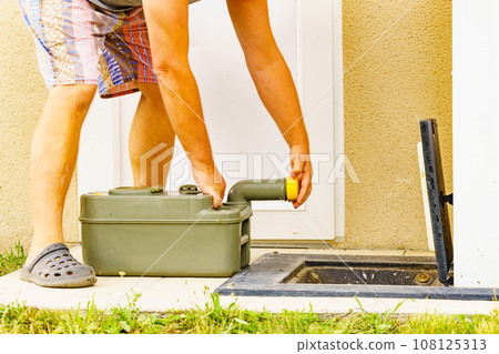 Man emptying caravan tank toilet cassette in dump station. 108125313