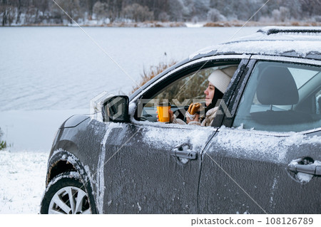 woman eat burger sitting in car at the frozen lake beach 108126789