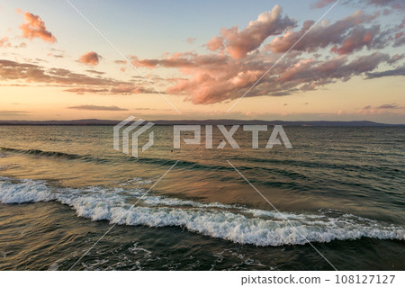 Sea surface with blue water waves under yellow and purple sunset sky. Sea surface with blue water waves under yellow and purple sunset sky. 108127127