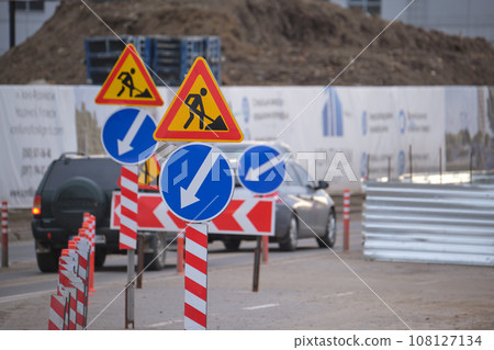 Roadworks warning traffic signs of construction work on city street and slowly moving cars Roadworks warning traffic signs of construction work on city street and slowly moving cars 108127134