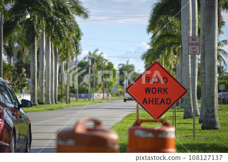 Road work ahead sign on street site as warning to cars about construction and utility works 108127137