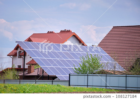 Private home with solar photovoltaic panels mounted on stand-alone frame on backyard ground for generating of clean ecological electric energy in suburban rural town area. Concept of autonomous house 108127184