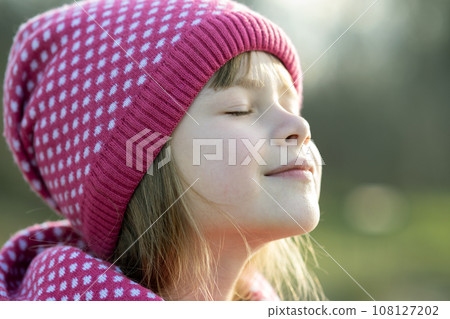 Pretty child girl in warm knitted winter clothes outdoors. 108127202