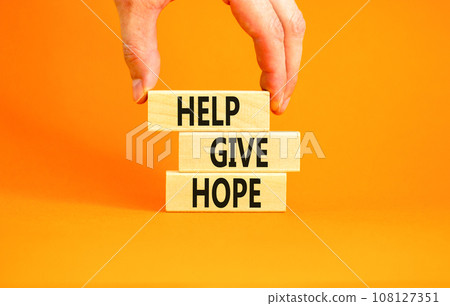 Help give hope symbol. Concept word Help give hope on beautiful wooden block. Businessman hand. Beautiful orange table orange background. Business motivational help give hope concept. Copy space. Help give hope symbol. Concept word Help give hope on beautiful wooden block. Businessman hand. Beautiful orange table orange background. Business motivational help give hope concept. Copy space. 108127351