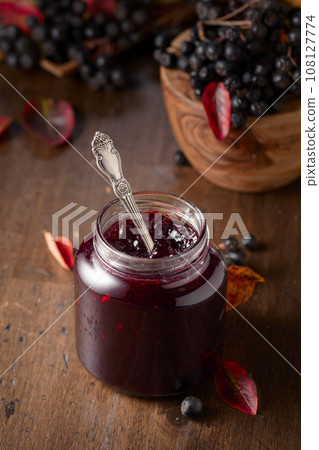 Chokeberry jam and fresh berries on an old wooden table. 108127774