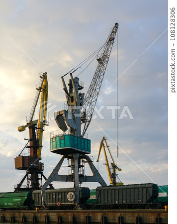 Harbor cranes with grain wagons between crane legs, seaport industry scene, grain export 108128306