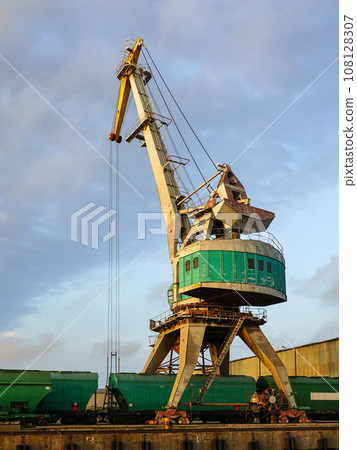 Harbor crane with grain wagons between crane legs, seaport industry scene, grain export 108128307