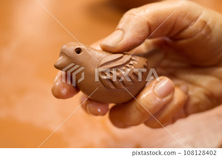 Unrecognizable potter master holding bird sculpture from clay clay in hand. 108128402