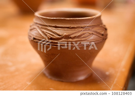 Ceramic shiny brown food pot standing on table, clay pot with pattern. Ceramic shiny brown food pot standing on table, clay pot with pattern. 108128403