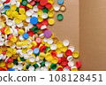 Used PET recycling plastic bottle cap plastic lids. Colorful bottle caps background cardboard box. Garbage PET waste recycling bottle cap sorting waste plastic garbage collection. Recyclable materials 108128451
