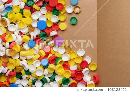 Used PET recycling plastic bottle cap plastic lids. Colorful bottle caps background cardboard box. Garbage PET waste recycling bottle cap sorting waste plastic garbage collection. Recyclable materials 108128451