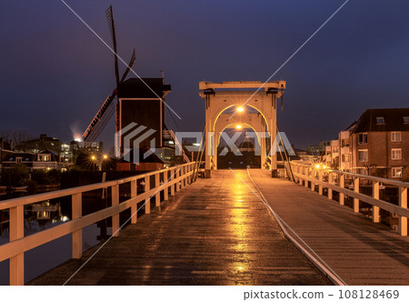 An old wooden mill on the banks of a canal in Leiden at dawn. 108128469