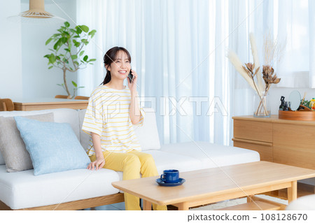 A young woman operating a smartphone in a room 108128670