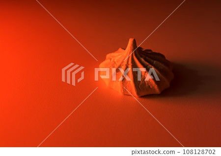One meringue cookie in red light on a light background. 108128702