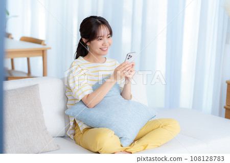 A young woman operating a smartphone in a room A young woman operating a smartphone in a room 108128783