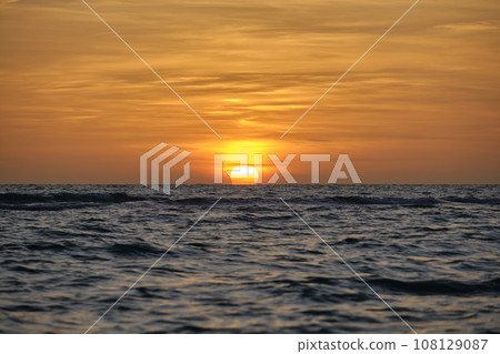 Ocean sunset. Big white sun on dramatic bright sky background, soft evening horizont over sea dark water 108129087