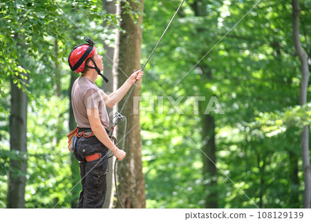 Man belays his partner climber with belaying device and rope. Climber's handsman holding equipment for rock mountaineering security. Man belays his partner climber with belaying device and rope. Climber's handsman holding equipment for rock mountaineering security. 108129139