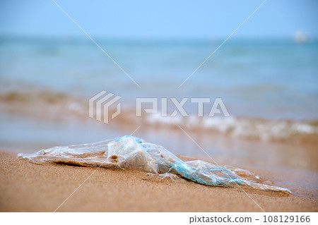 Left behind plastic bag garbage on sandy beach. Empty used dirty litter on sea shore. Environmental pollution. Ecological problem 108129166