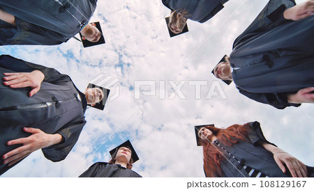 Graduates in black robes stand in a circle. Graduates in black robes stand in a circle. 108129167