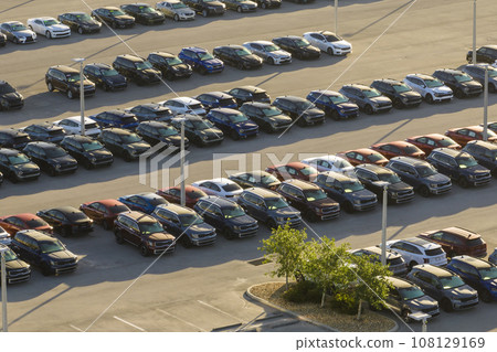Large parking lot of local dealer with many brand new cars parked for sale. Development of american automotive industry and distribution of manufactured vehicles concept 108129169