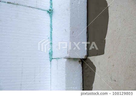 Installation of styrofoam insulation sheets on house facade wall for thermal protection. 108129803