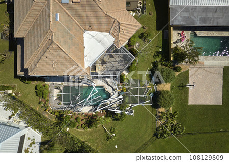 Hurricane Ian destroyed house roof in Florida residential area. Natural disaster and its consequences 108129809