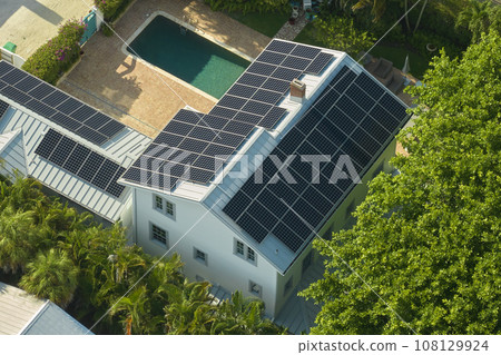 Expensive american residential house with rooftop covered with solar photovoltaic panels for producing of clean ecological electrical energy in suburban rural area. Concept of autonomous home Expensive american residential house with rooftop covered with solar photovoltaic panels for producing of clean ecological electrical energy in suburban rural area. Concept of autonomous home 108129924
