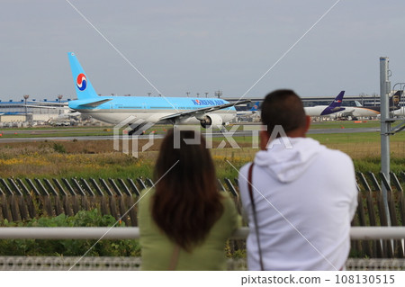 A female couple seeing off a passenger plane taking off 108130515