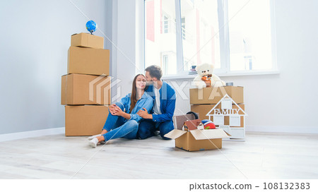 Caucasian couple moving in new home. Young stylish couple in moving in mess. Caucasian couple moving in new home. Young stylish couple in moving in mess. 108132383