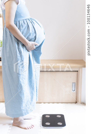 Pregnant woman standing in front of a scale Pregnant woman standing in front of a scale 108134646