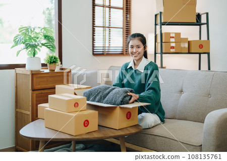 Starting small business entrepreneur of independent Asian female online seller packing products to send to customers and SME delivery concept. Starting small business entrepreneur of independent Asian female online seller packing products to send to customers and SME delivery concept. 108135761
