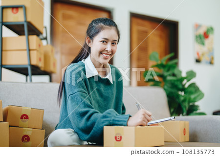 Starting small business entrepreneur of independent Asian female online seller packing products to send to customers and SME delivery concept. Starting small business entrepreneur of independent Asian female online seller packing products to send to customers and SME delivery concept. 108135773
