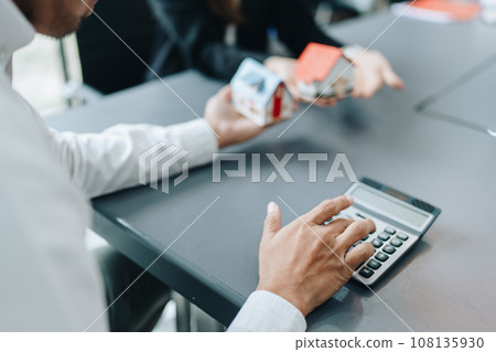 Guarantee, mortgage, contract, contract, signed, real estate agent or bank officer holding a calculator, submits a bid with a customer to buy a home before signing to make a deal. Guarantee, mortgage, contract, contract, signed, real estate agent or bank officer holding a calculator, submits a bid with a customer to buy a home before signing to make a deal. 108135930