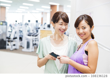 Young woman looking at a smartphone at a sports gym 108136128