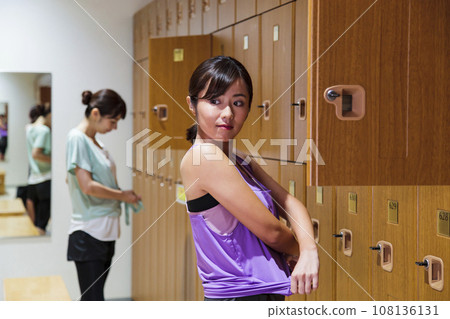 Young woman changing clothes in the locker room of a sports gym Young woman changing clothes in the locker room of a sports gym 108136131