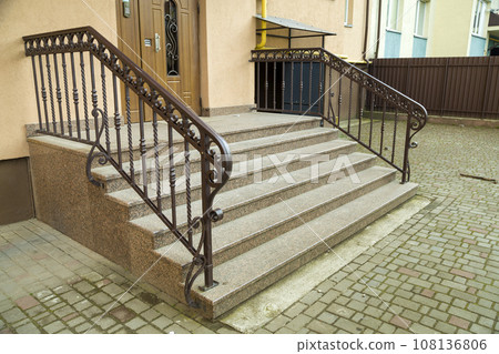 Detail of a house facade. New granite stairs with metal railings. 108136806