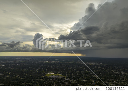 Dark stormy clouds forming on gloomy sky during heavy rainfall season over suburban town area 108136811