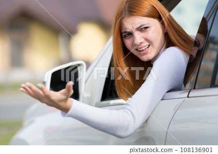 Closeup portrait of pissed off displeased angry aggressive woman driving a car shouting at someone with hand up. Negative human expression consept. Closeup portrait of pissed off displeased angry aggressive woman driving a car shouting at someone with hand up. Negative human expression consept. 108136901