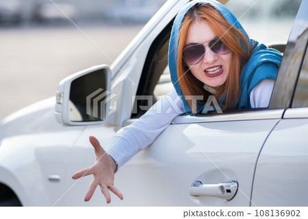 Closeup portrait of pissed off displeased angry aggressive woman driving a car shouting at someone with hand fist up. Negative human expression consept. Closeup portrait of pissed off displeased angry aggressive woman driving a car shouting at someone with hand fist up. Negative human expression consept. 108136902